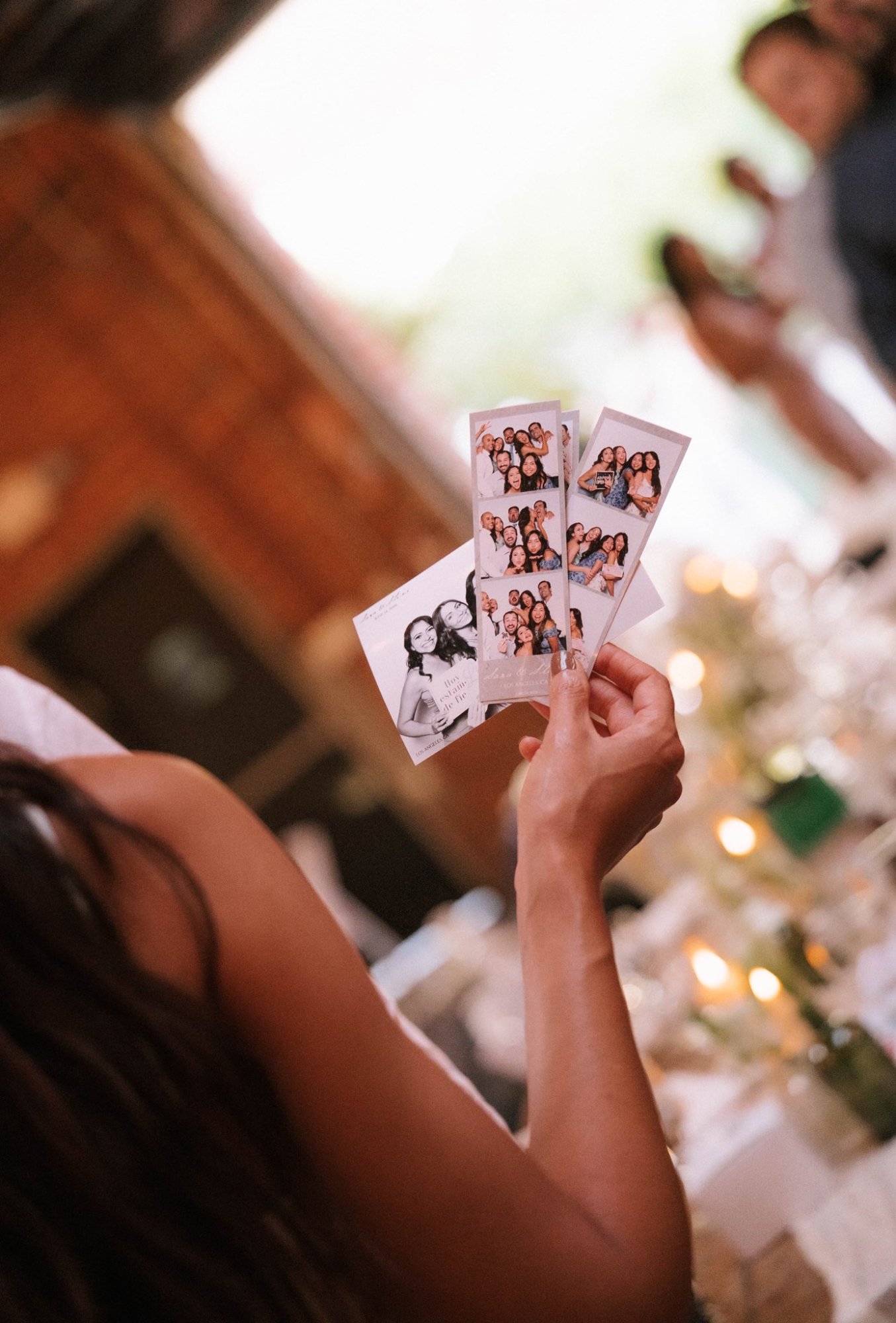 A person holding several photo booth strips at a table